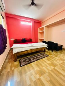 um quarto com uma cama e uma parede vermelha em Mangalam guest house em Puri