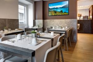 a restaurant with tables and chairs and a tv on the wall at Rome Art Hotel - Gruppo Trevi Hotels in Rome