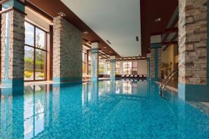 a large swimming pool with blue water in a building at Pirin Bliss Apartment Ski, Spa and Relax at Terra Complex in Razlog