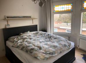 a bedroom with a bed with a comforter and a window at Nice apartment next to the beach in Scheveningen