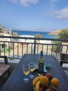 un tavolo con 2 bicchieri di vino e frutta sul balcone di ANDRIANOS DELUXE STUDIO a Mátala