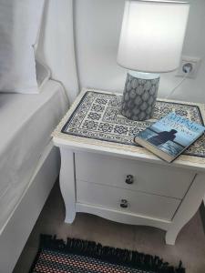 a bedside table with a lamp and a book on it at ANDRIANOS DELUXE STUDIO in Matala