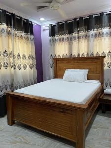 Cama grande de madera en habitación con cortinas en Bagamoyo Home Stay en Bagamoyo