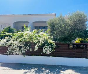 a fence with white flowers in front of a building at Mermaid Holiday Apartments in Mandria