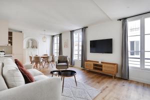 ein Wohnzimmer mit einem Sofa und einem TV in der Unterkunft Pick A Flat's Apartments in Opéra - Rue d'Hauteville in Paris