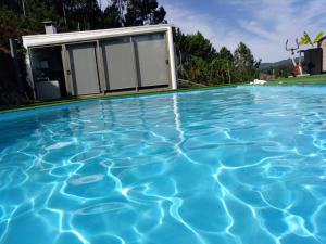 a swimming pool with blue water in front of a house at Casa Rocha Velha con piscina y terraza particular in Santiago de Compostela