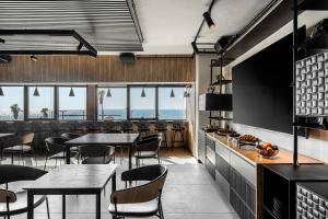 a restaurant with tables and chairs and windows at Prima Tel Aviv Hotel in Tel Aviv