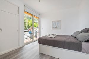 a white bedroom with a bed and a large window at Magical Sunset in Madalena do Mar