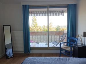 een slaapkamer met een raam met uitzicht op een balkon bij Appartement 2 P 5 PER ENTRE BEAUVAL & CHENONCEAU in Montrichard