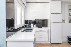 a white kitchen with a sink and a refrigerator at BHost - Tendillas in Córdoba