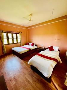 a hotel room with two beds and two windows at Hotel Tree Tops in Sauraha