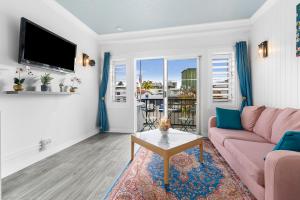 sala de estar con sofá rosa y TV en Villa Vaucluse Apartments, en Cairns