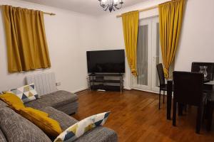 ein Wohnzimmer mit einem Sofa, einem Tisch und einem TV in der Unterkunft Private 2 Bed Flat close to EXCEL & CITY AIRPORT in London