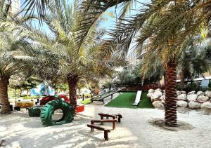 a park with benches and palm trees and a playground at Letstay - Misty Rosa 1BR Apartment in Dania 3 With Balcony in Dubai