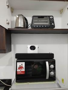 a microwave sitting on top of a kitchen counter at Homey Studio at Stamford Mckinley hill few walk to Venice Piazza in Manila