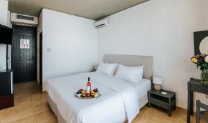 a bed with a bowl of fruit and a bottle of wine at Apollo Resort in Agia Marina Aegina