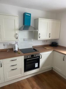 uma cozinha com armários brancos e um forno com placa de fogão em May Disc - Long Stay - Contractors em Bristol