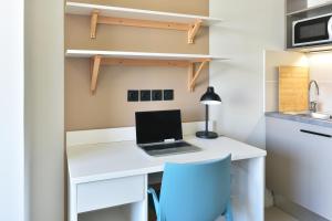 a desk with a laptop and a blue chair in a kitchen at Student Factory Toulouse Zénith in Toulouse