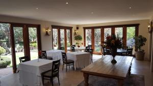 un comedor con mesas y sillas blancas y ventanas en Black Eagle Hotel & Spa en Roodepoort