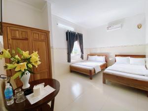 una habitación con 2 camas y una mesa con flores. en khách sạn sơn hạ, en Kon Tum