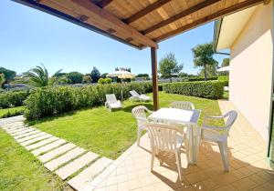 a patio with a white table and chairs on the grass at ISA-Residence with swimming pool in Mazzanta at only 600 meters from the beach, apartments with air conditioning and private outdoor area in Mazzanta
