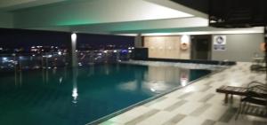 a swimming pool with a view of a city at night at PINTARMAN SERVICE APRTMENT @ THE STIRLING SUITES in Miri