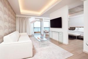 ein Wohnzimmer mit einem weißen Sofa und einem TV in der Unterkunft Mediterranean Hotel in Rhodos (Stadt)