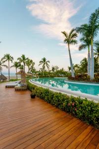 a swimming pool with palm trees and a wooden deck at Grand Luxxe Two Bedroom Villa- Nuevo Vallarta in Nuevo Vallarta