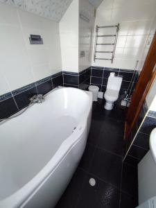 La salle de bains est pourvue d'une baignoire blanche et de toilettes. dans l'établissement Садиба АнноМарі - відпочинок в Карпатах котедж Яремче, à Yaremtche