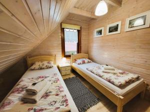 a room with two beds in a wooden cabin at Domki Lawendowy Zakątek in Boszkowo