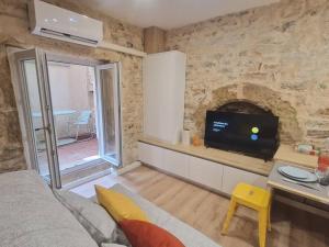 een woonkamer met een tv en een stenen muur bij Studio plein centre-ville 2 in Nîmes