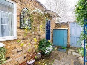 une maison en briques avec une porte bleue et des plantes dans l'établissement Pass the Keys Cozy studio flat in trendy Brixton, à Londres