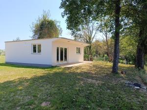 a small white house in a field with a tree at Riverhouse Žeger in Prijedor