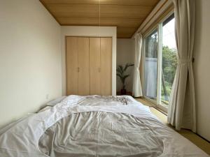 1 cama blanca en un dormitorio con ventana en 南あその丘 en Shimoda