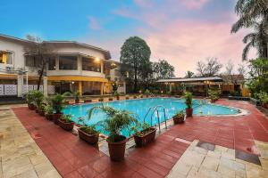 a swimming pool with potted plants next to a building at Manas Lifestyle Resort, Igatpuri in Igatpuri