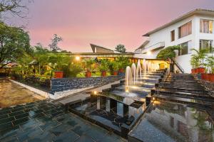 a house with a fountain in front of a building at Manas Lifestyle Resort, Igatpuri in Igatpuri