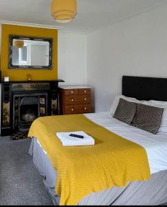 a bedroom with a bed with a yellow blanket and a fireplace at Golden Triangle Rooms in Norwich