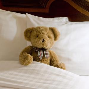 un oso de peluche marrón sentado en una cama en Holiday Inn Arlington at Ballston, an IHG Hotel en Arlington