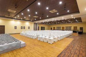 Habitación grande con filas de sillas blancas. en Manas Lifestyle Resort, Igatpuri, en Igatpuri