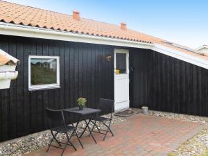a black house with a table and chairs in front of it at 8 person holiday home in Harbo re in Harboør