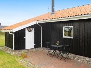 a black building with a table and chairs in front of it at 8 person holiday home in Harbo re in Harboør
