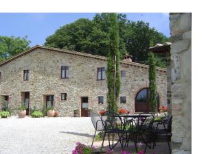 a stone building with a table and chairs in front of it at Podere Le Ghiande in CastellʼAzzara