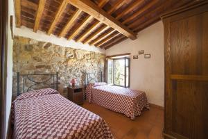 a bedroom with two beds and a stone wall at Podere Le Ghiande in CastellʼAzzara