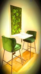 two green chairs and a table with a painting on the wall at suite st lo 2 in Rouen