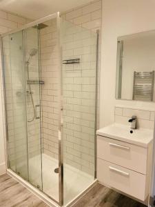 a bathroom with a glass shower and a sink at Stunning huge openplan 2Bed flat in Woking