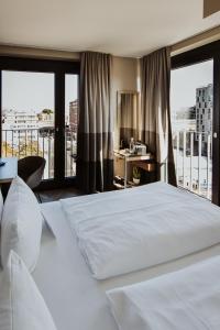 a bedroom with a large white bed and a balcony at Emma by Schulz Hotel Berlin Friedrichshain in Berlin