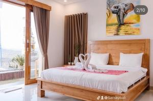 a bedroom with a bed with an elephant picture on the wall at Sari Sky Bali in Kubupenlokan