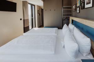 a bedroom with two beds with white sheets and pillows at Emma by Schulz Hotel Berlin Friedrichshain in Berlin