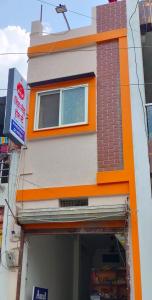 een oranje en grijs gebouw met een raam bij SHIV SNEH HOME STAYS in Ujjain