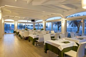 un restaurante con mesas blancas, sillas blancas y ventanas en Al Mirador Resort, en Selva di Fasano